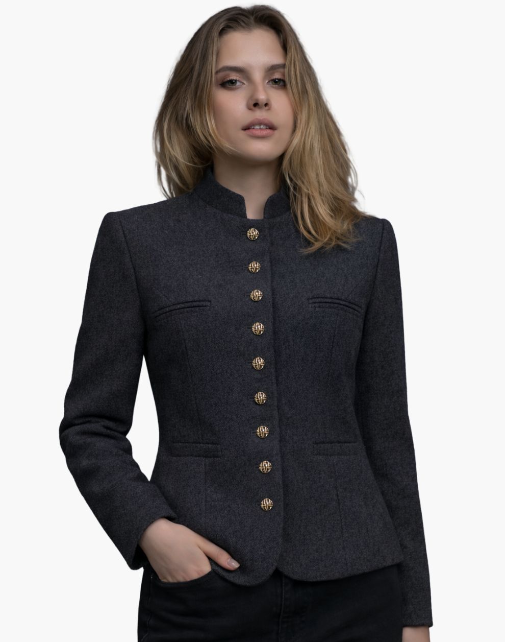 Front view of a woman wearing a charcoal grey tailored jacket with a stand-up collar and a vertical row of decorative gold-tone buttons down the front. The jacket features subtle welt pockets and a gently flared hem, paired with dark jeans. The background is plain light gray, giving the image a simple studio look.