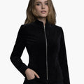 Female model wearing a black velvet jacket with a high collar and front zipper, featuring a sleek tailored fit.