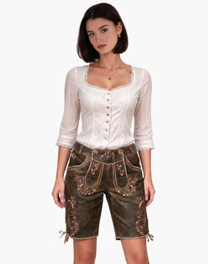 Woman wearing a traditional outfit with a white blouse and brown shorts on a white background