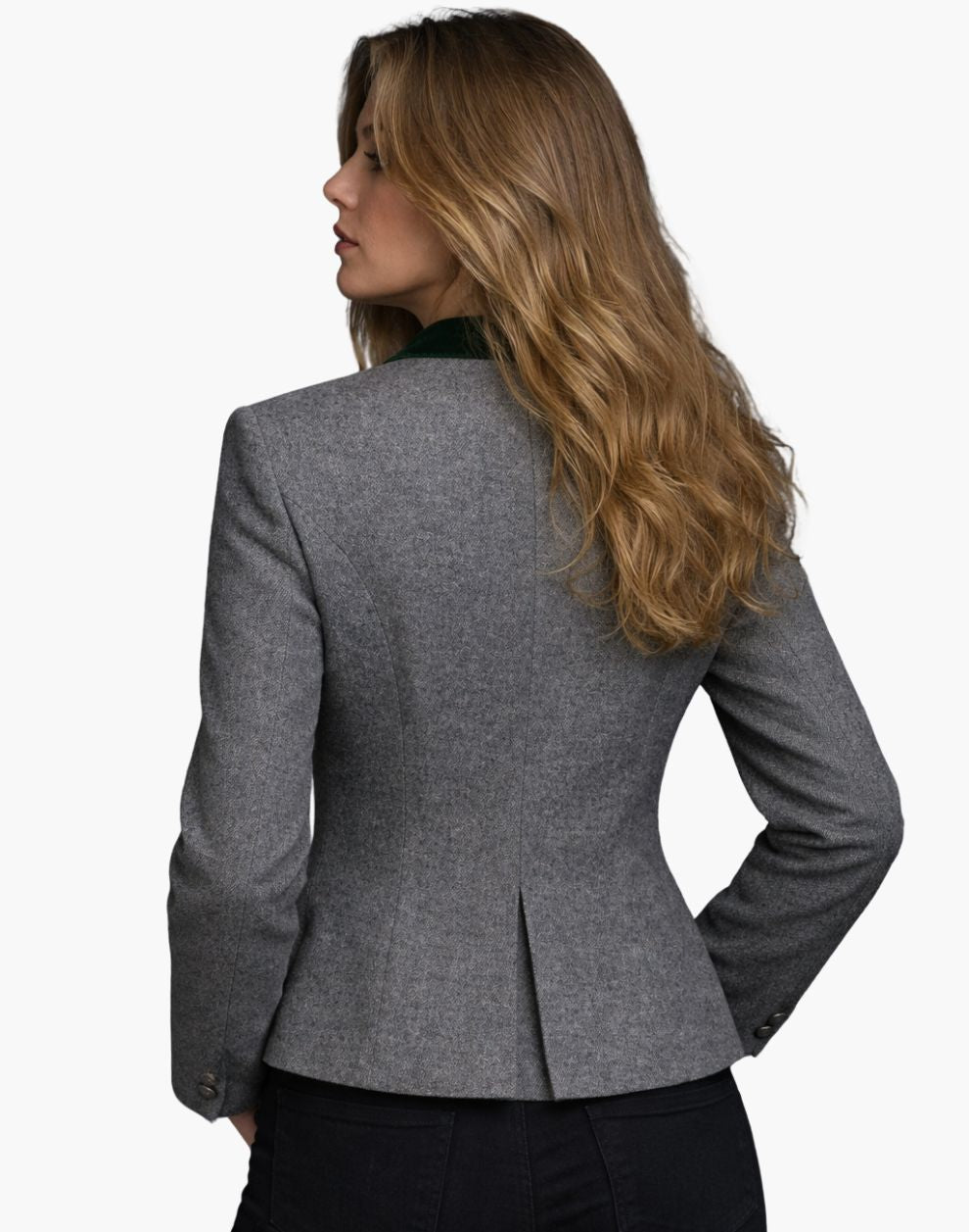 Back view of a woman wearing the same fitted gray wool jacket, showing structured seams that contour the waist and a small center back vent. The collar has a dark green accent, and she pairs the jacket with dark jeans. Her shoulder-length blonde hair falls loosely over the collar. The background is plain light gray.