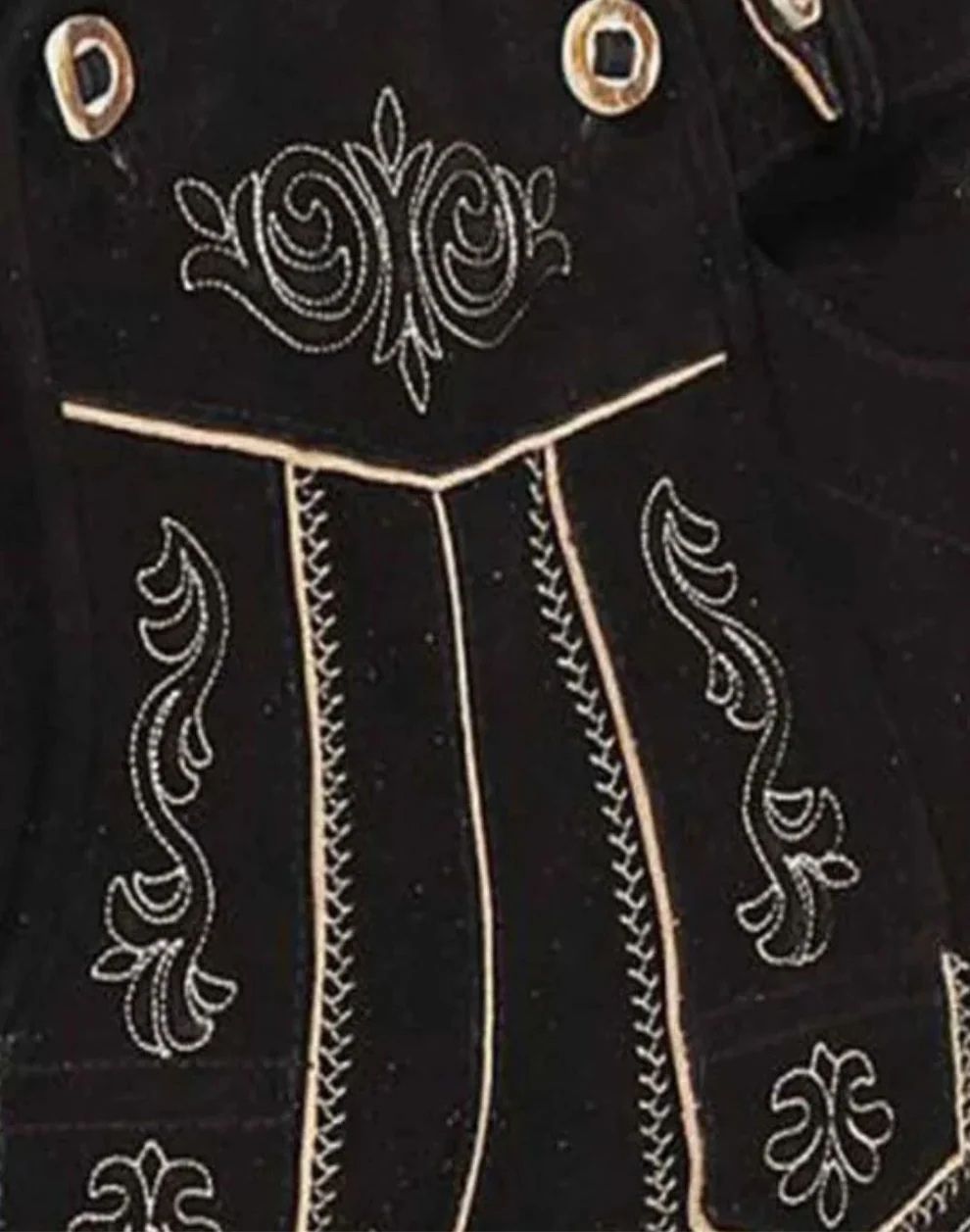 Close-up of a black garment with intricate white embroidery on a dark background