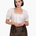 Woman wearing a white blouse with lace details and brown traditional shorts on a white background