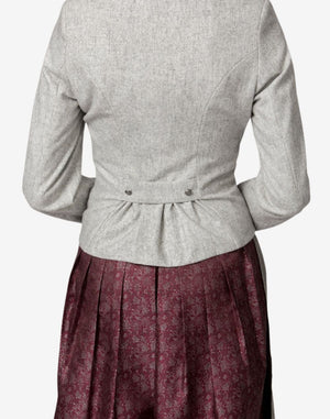Close-up back view of a women’s light grey traditional Bavarian trachten jacket featuring a fitted waist with pleated back detail, worn over a burgundy patterned dirndl skirt.