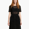 Woman wearing a black dress with sheer panels on a white background