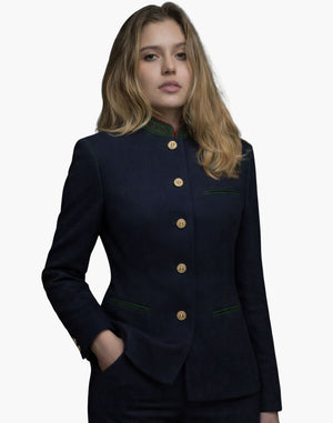 Front view of a woman wearing a deep navy tailored jacket with a stand-up collar accented in green and red trim. The jacket has a vertical row of gold-tone buttons, green-trimmed welt pockets, and a fitted silhouette, styled with dark trousers. The background is plain light gray.
