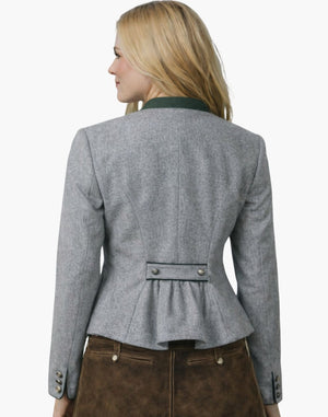 Back view of a woman wearing an authentic alpine Trachten jacket in light grey with a green collar, fitted waist, and pleated back detail, paired with brown lederhosen, against a white background.