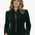 Woman wearing a green velvet Trachten jacket with traditional buttons, fitted silhouette, and classic Bavarian design, paired with brown lederhosen, against a white background.