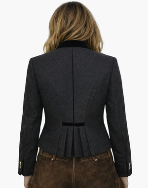 Back view of a woman wearing a traditional German Trachten jacket in dark grey with a fitted waist, pleated back detail, and tailored Bavarian design, paired with brown lederhosen, against a white background.