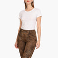 Woman wearing brown traditional pants with a white top on a white background